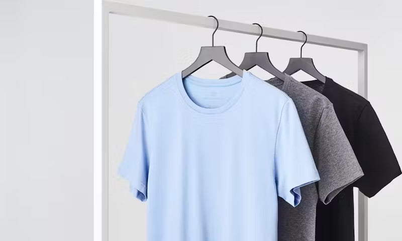 image of a baby blue, grey, and black crew neck t-shirts on hangers 