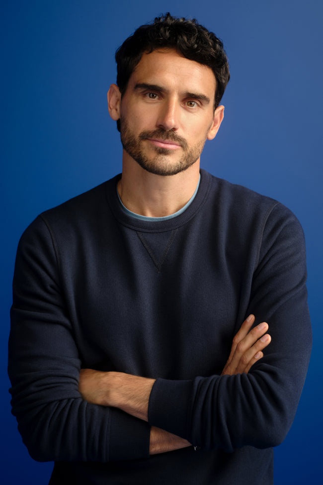 Man crossing his arms wearing a navy blue sweater