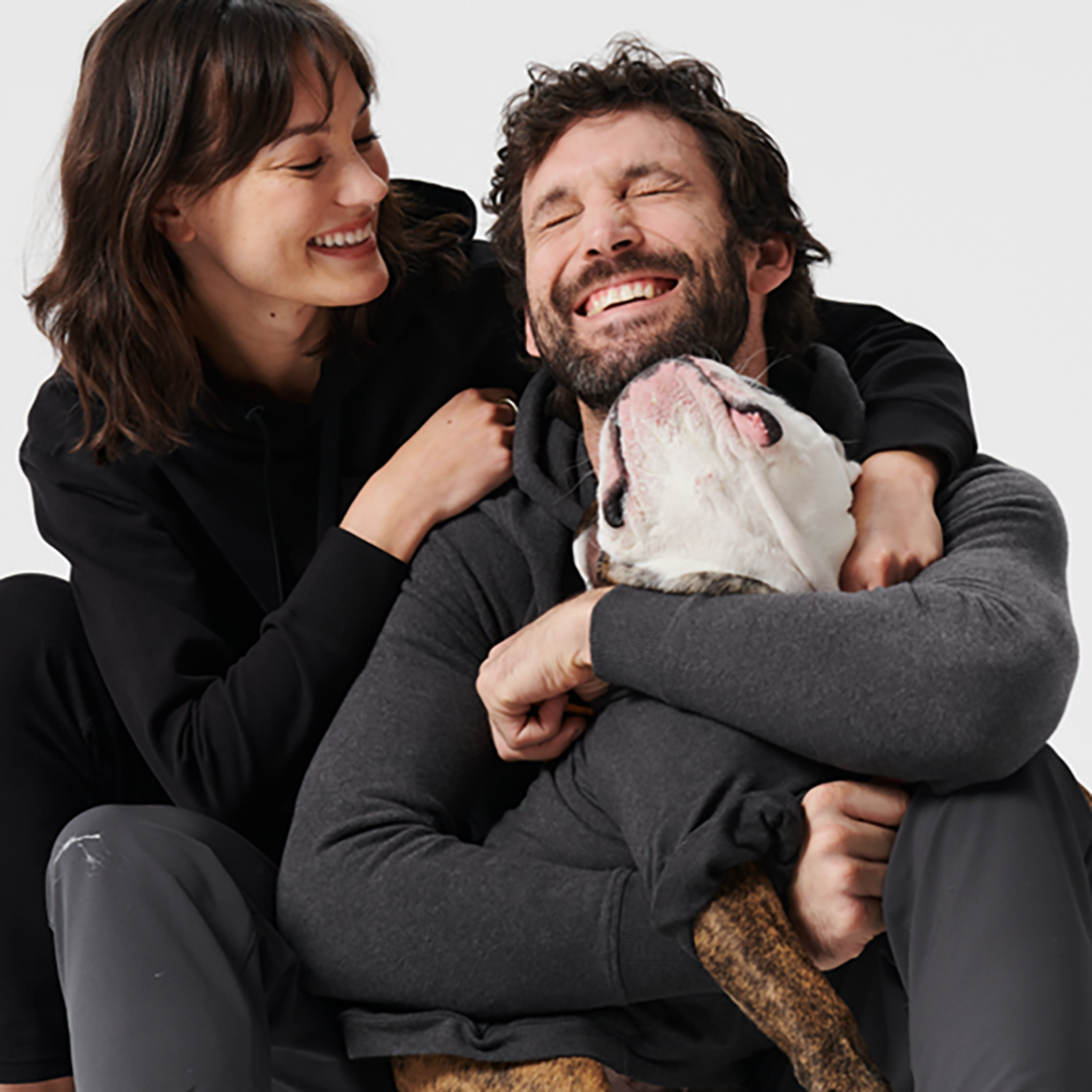 image of a man and woman playing with a dog and smiling
