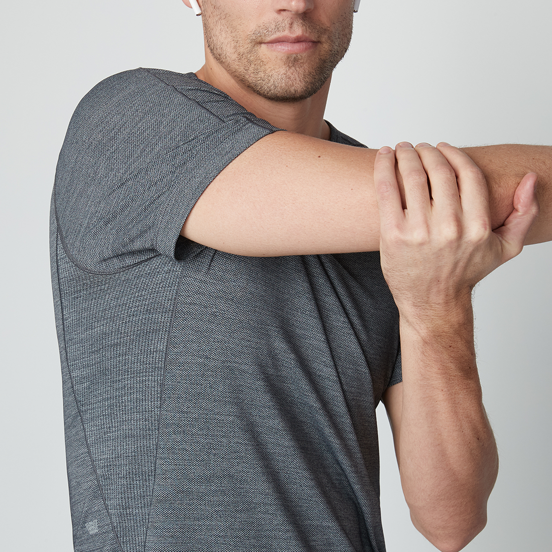 man wearing an AIRKNITx shirt stretches his arm across his chest