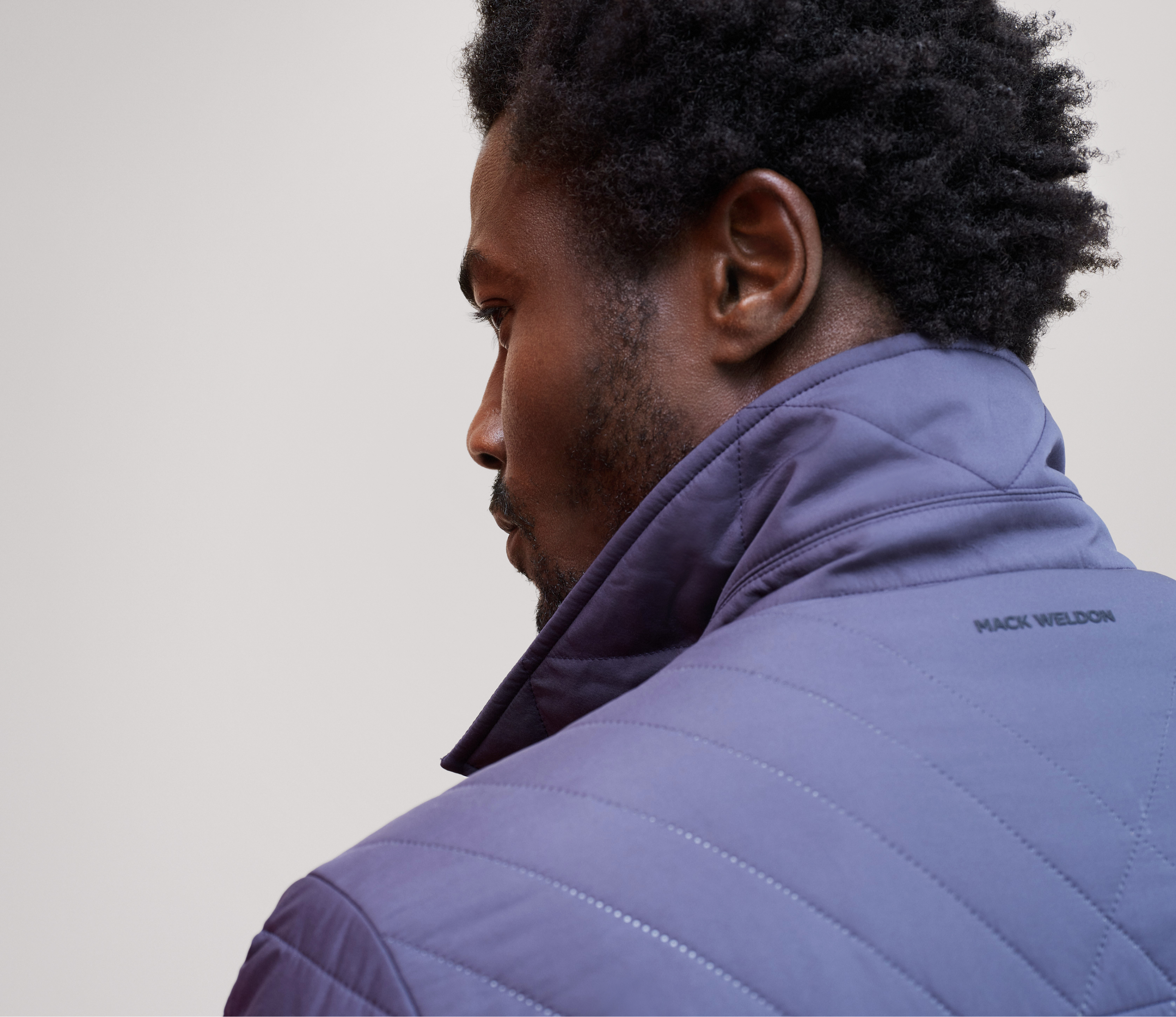 Back of a man wearing a navy blue quilted winter jacket