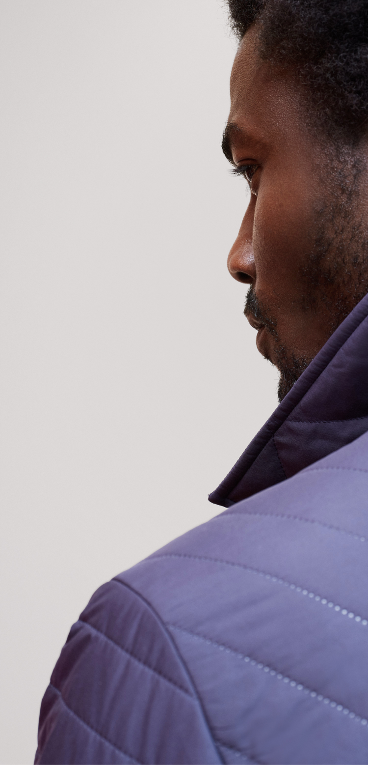 Back of a man wearing a navy blue quilted winter jacket